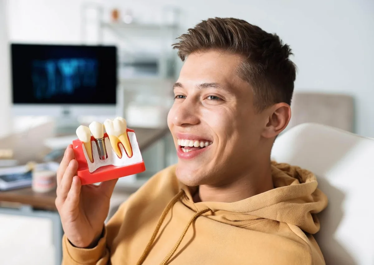 Patient holding a dental implant model while learning about the tooth implant timeline.