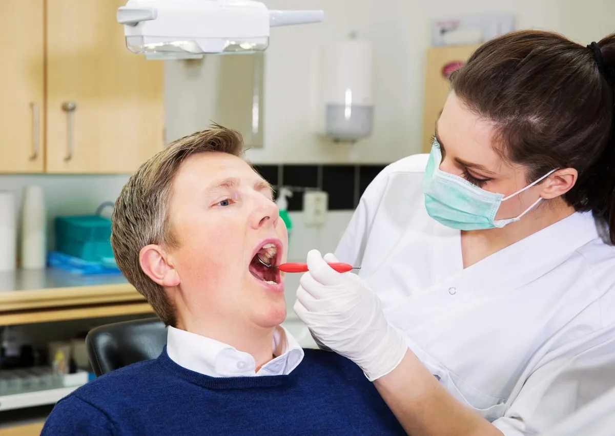 Dentist examining a patient’s mouth to check for a normal socket after tooth extraction.