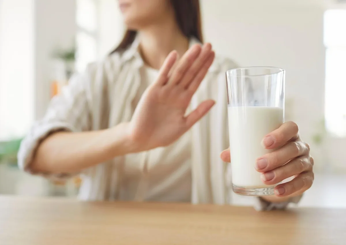 Person avoiding a glass of milk while following dietary guidelines after dental implant surgery.