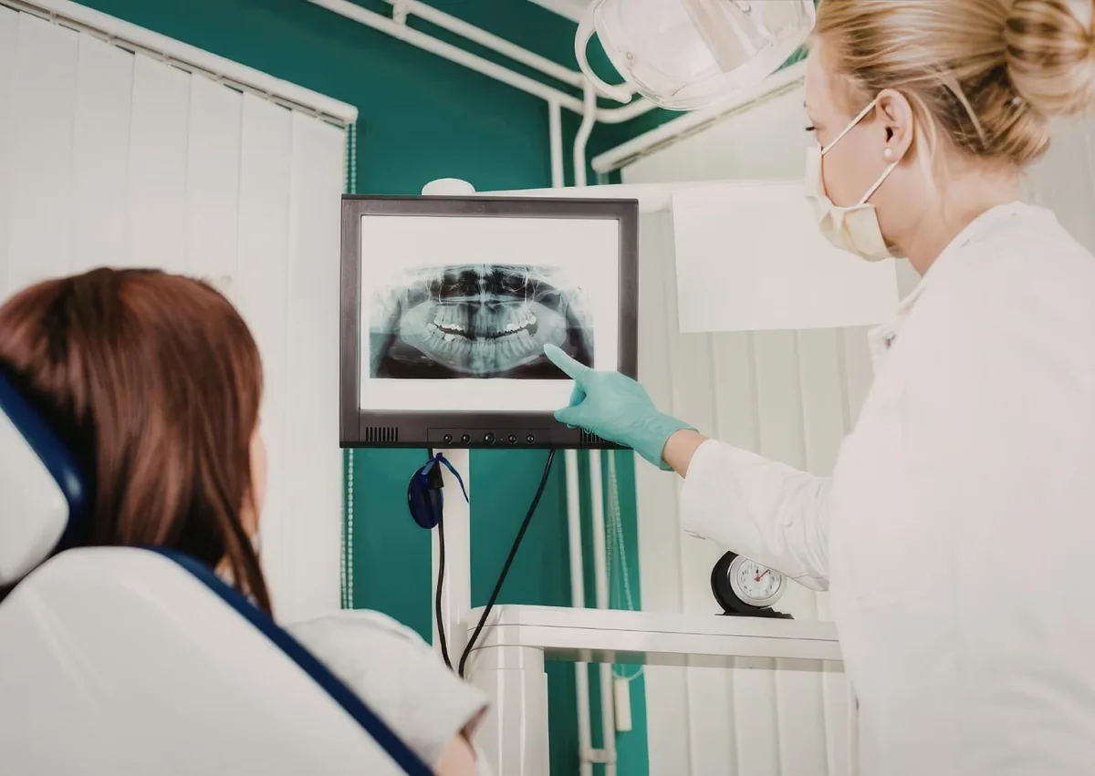 Dentist reviewing a panoramic X-ray with a patient while planning zygomatic dental implants.
